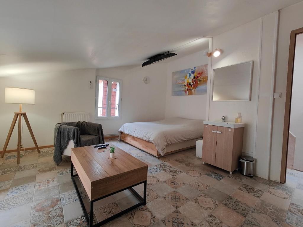 une chambre avec un lit et une table dans une pièce dans l'établissement Maison 2 chambres 100m du Théâtre Antique avec salle cinéma, à Orange