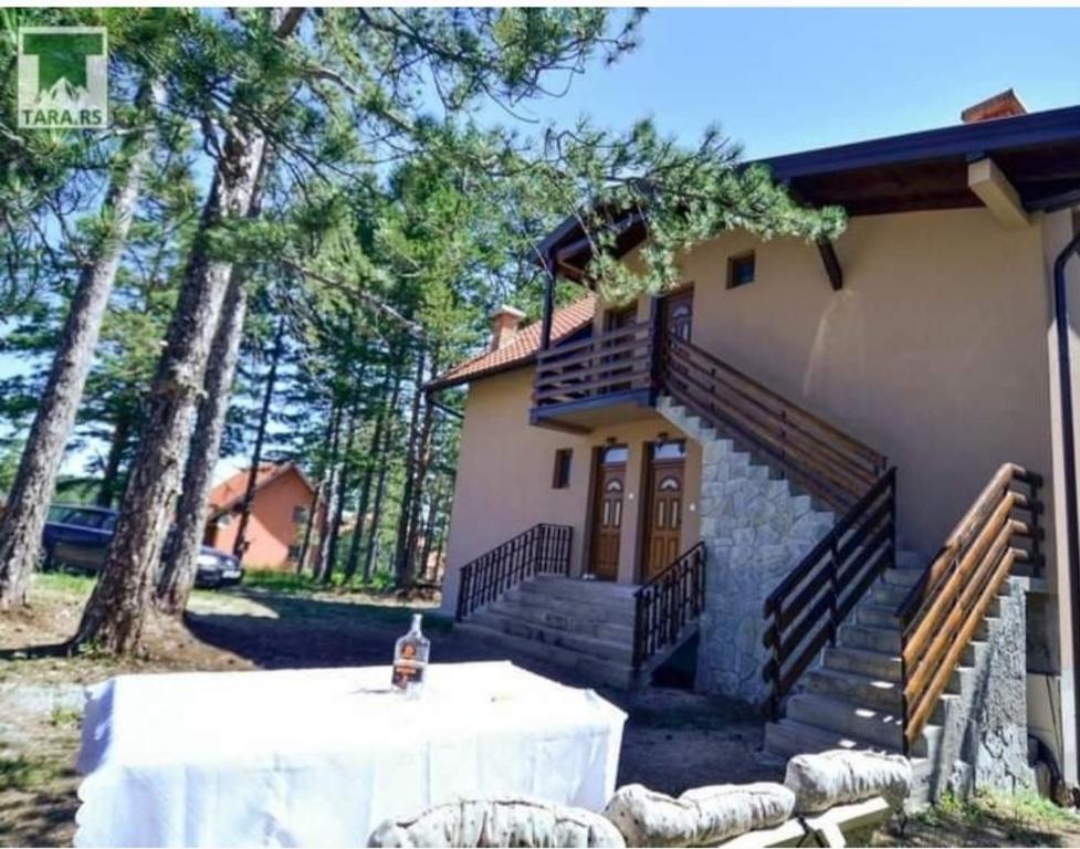 a table in front of a house with trees at Apartman NIKOLIJA 1 in Bajina Bašta