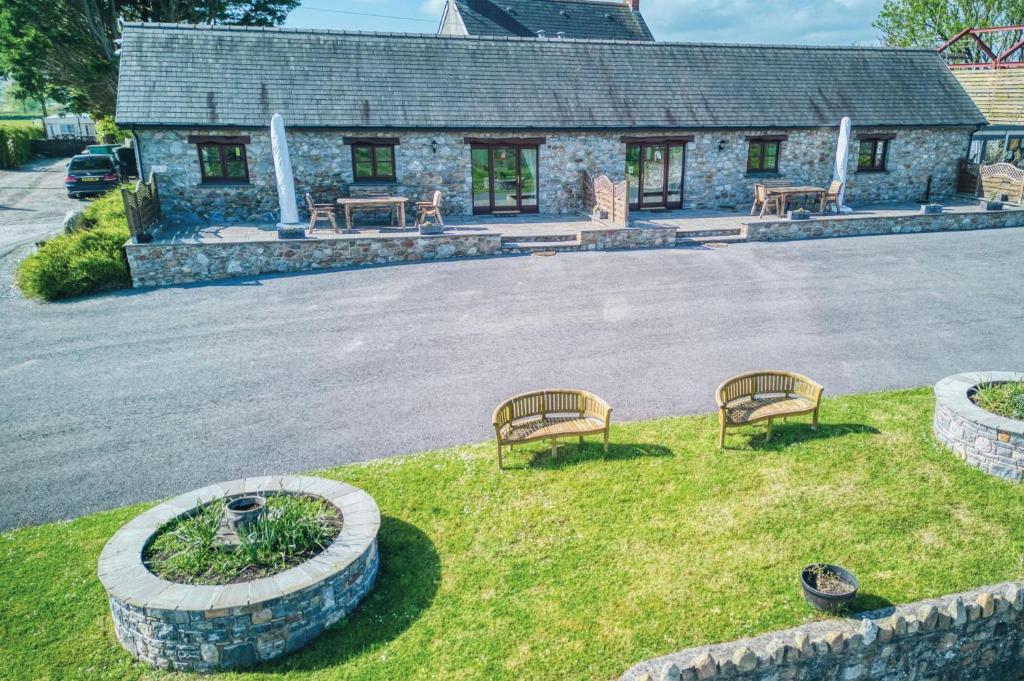 two benches sitting in the grass in front of a building at Ocean View Cottage 2 - 2 Bed Cottage - Llanrhidian in Llanrhidian