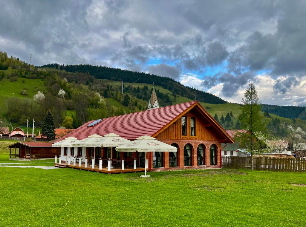 duży budynek z parasolami na polu trawy w obiekcie Biotour Camping & Restaurant w mieście Ghimeş