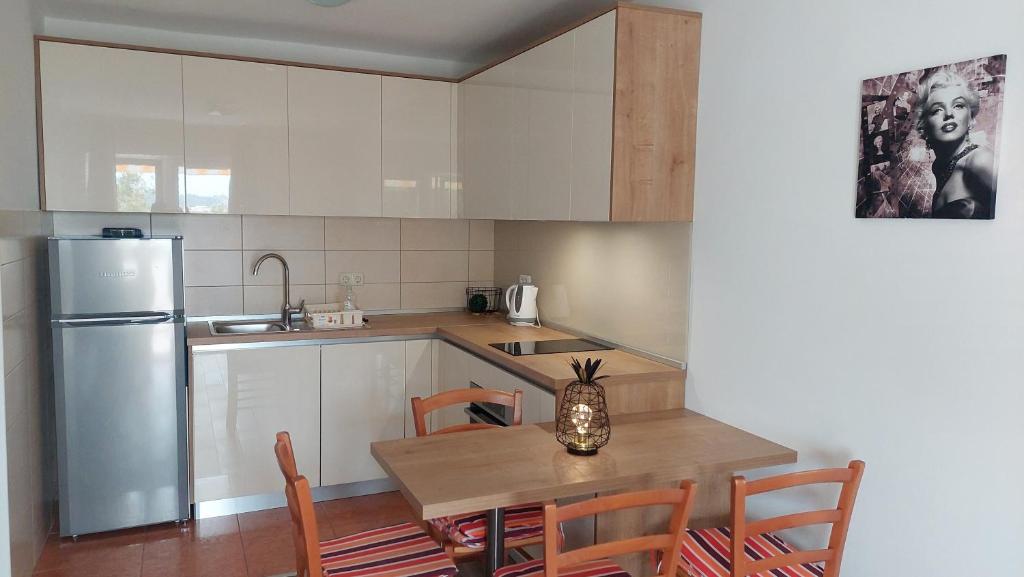 a kitchen with a wooden table and a refrigerator at Apartments Nikola Caska in Novalja