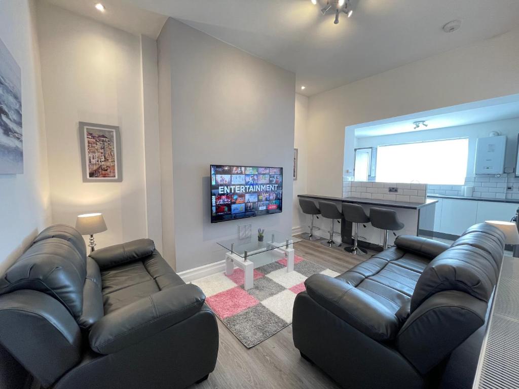 a living room with black leather furniture and a flat screen tv at Jacksons Modern Retreat Close to Tynemouth in Tynemouth