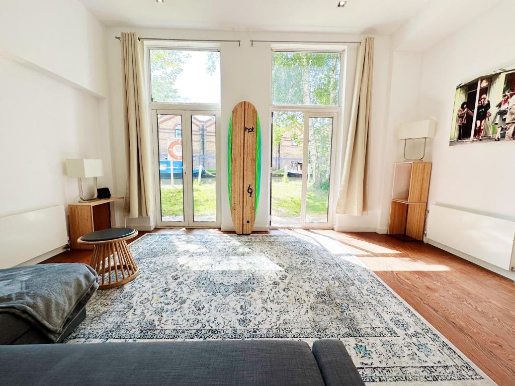 a living room with a surfboard in front of a door at Portobello Dock Canalside Apartment in London