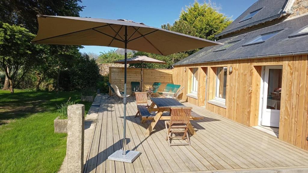 une terrasse en bois avec une table, des chaises et un parasol dans l'établissement Kermaria- Maison 10 pers - 4km Mer - Paimpol-Treguier, à Pleumeur-Gautier