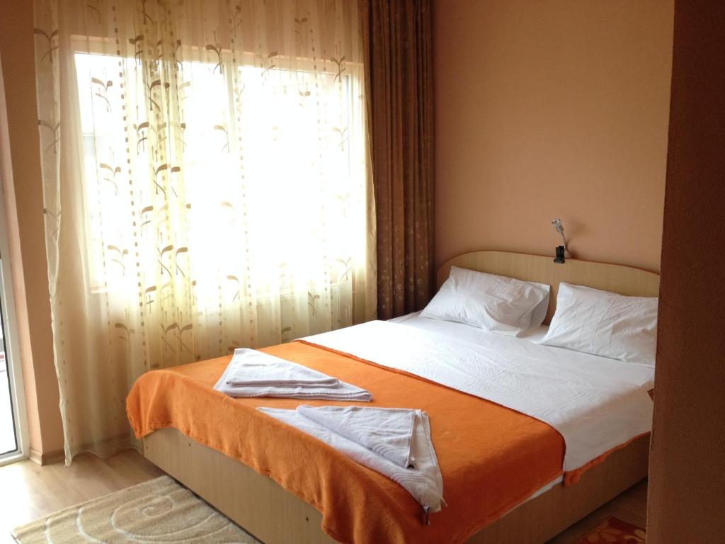 1 dormitorio con 1 cama con manta naranja y ventana en Casa Mario, en 2 Mai