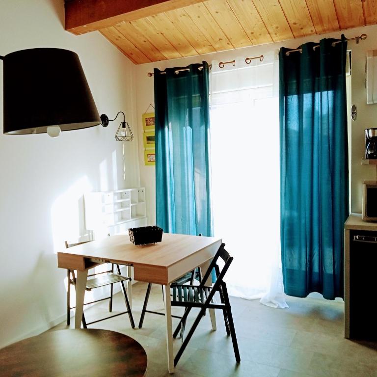 comedor con mesa de madera y cortinas azules en Magnifique appartement avec terrasse Roof-Top, en Saint-Étienne