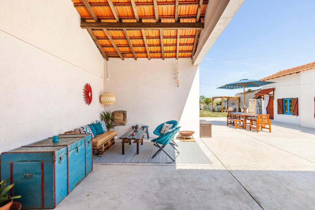 eine Terrasse mit einem Tisch, Stühlen und einem Sonnenschirm in der Unterkunft Bloomoon House in Bunheiro