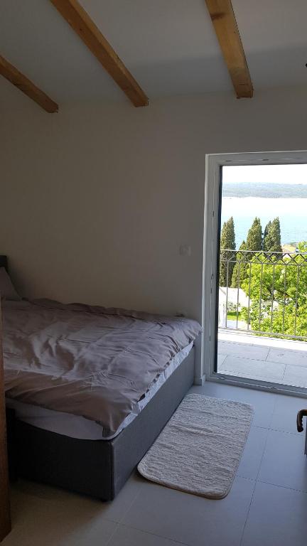 - une chambre avec un lit et une grande fenêtre dans l'établissement Apartman Nagy, à Dramalj