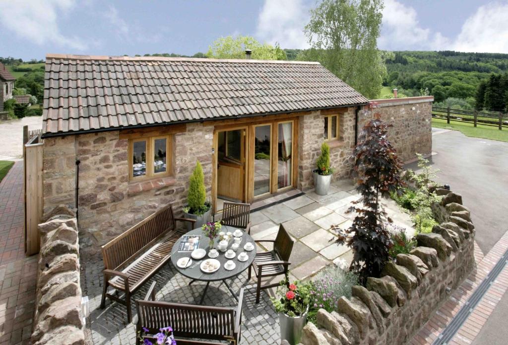 a small stone cottage with a table and chairs at Meadow Byre in Little Dean