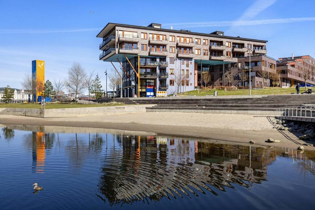 a building with a reflection in a body of water at Beachfront apartment Sørenga Oslo in Oslo