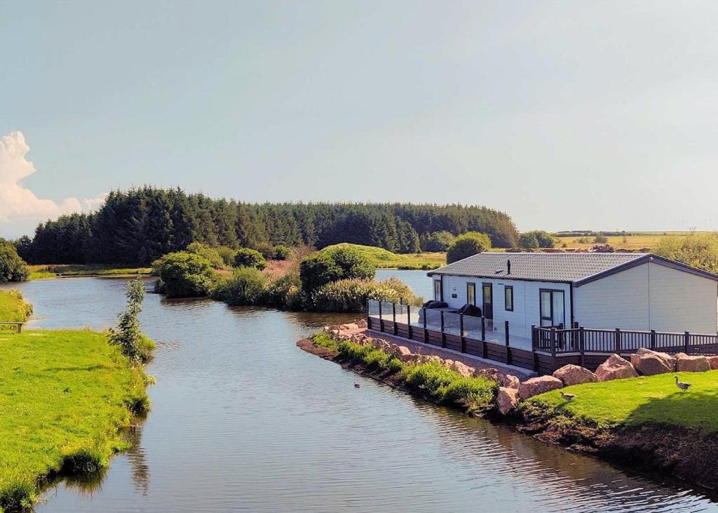 a building sitting on the side of a river at Luxury Lakeside Lodge with HTub Beautiful Views in Annan