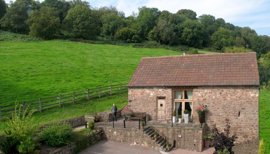 a stone house in a field with a person standing outside at Orchard Barn in Little Dean