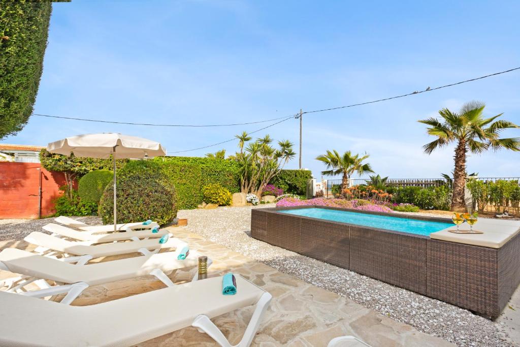 マルグラット・デ・マルにあるVilla Erika Beach Houseのラウンジチェアとパラソル付きのプールを併設しています。