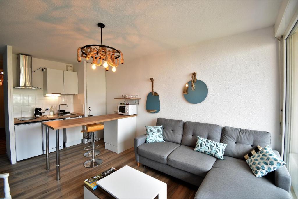 a living room with a couch and a kitchen at Point d'or H - Joli appartement rénové au bord de l'océan in Soorts-Hossegor