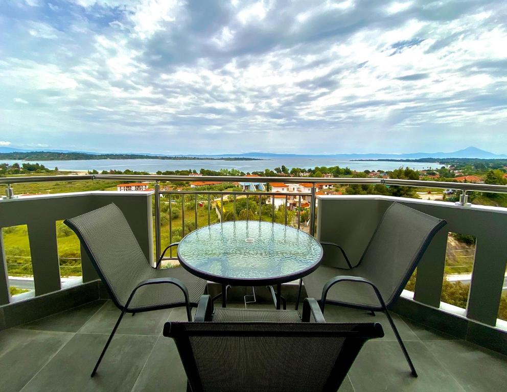 een tafel en stoelen op een balkon met uitzicht bij THEA Luxury Apartments in Vourvourou