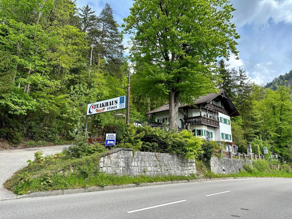 uma casa ao lado de uma estrada com um sinal em Pension Steakhaus Füssen em Füssen