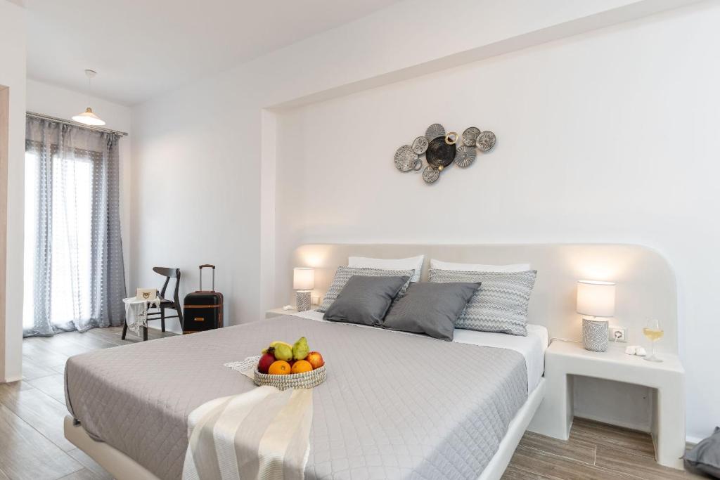 a white bedroom with a bed with a bowl of fruit on it at Naxian Air in Agios Georgios