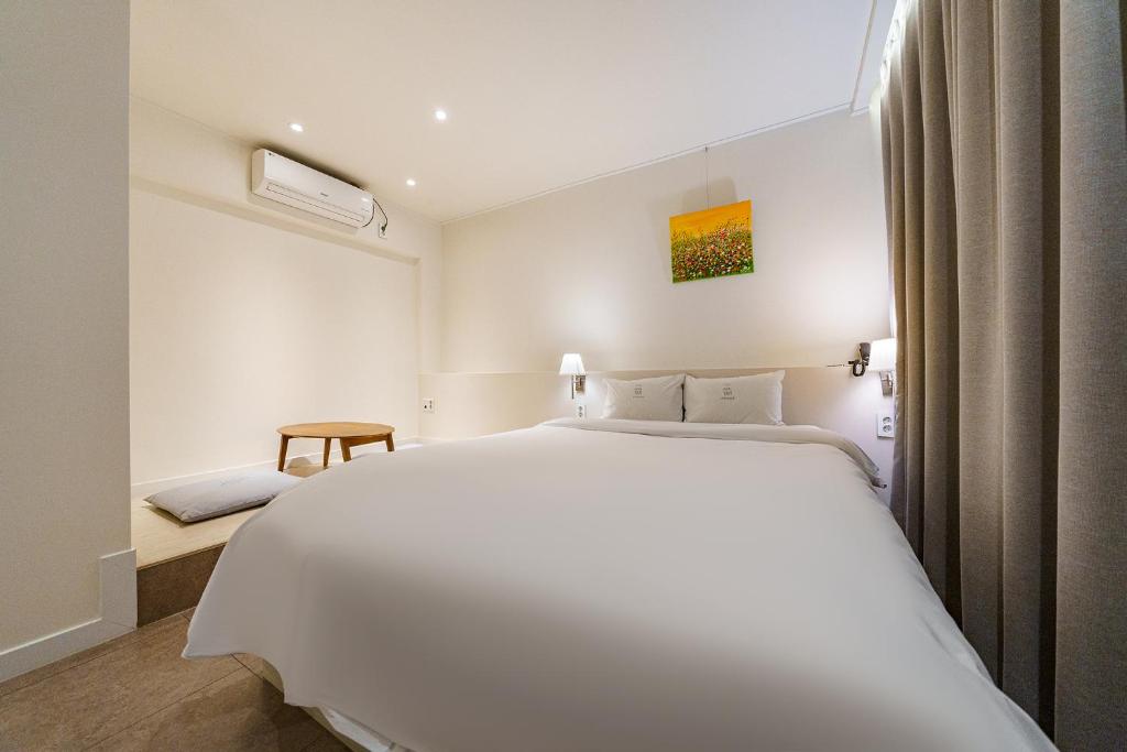 a bedroom with a large white bed and a window at Hotel Yam Gumi in Gumi