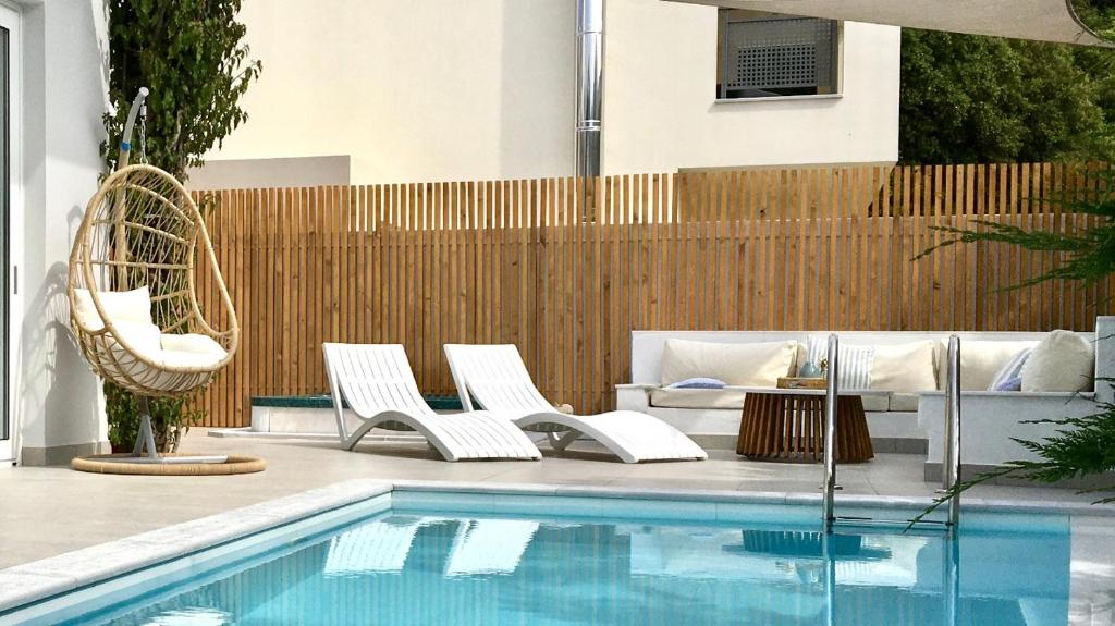 basen z białymi leżakami i ogrodzeniem w obiekcie Chris Rea Villa w mieście Skiatos