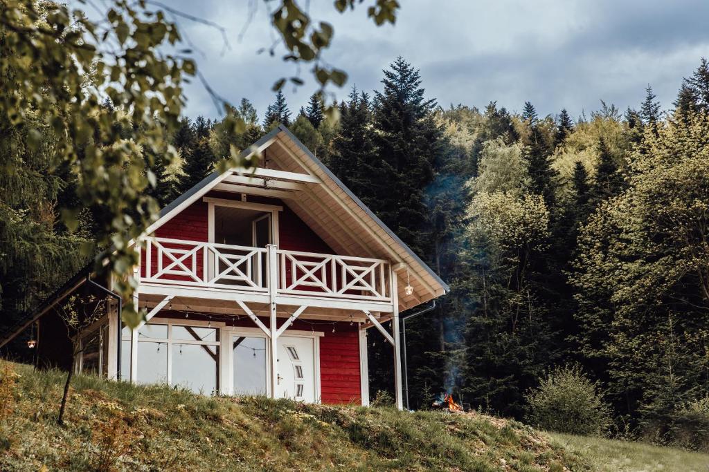 una casa roja y blanca en una colina con árboles en Forest house, en Targanice