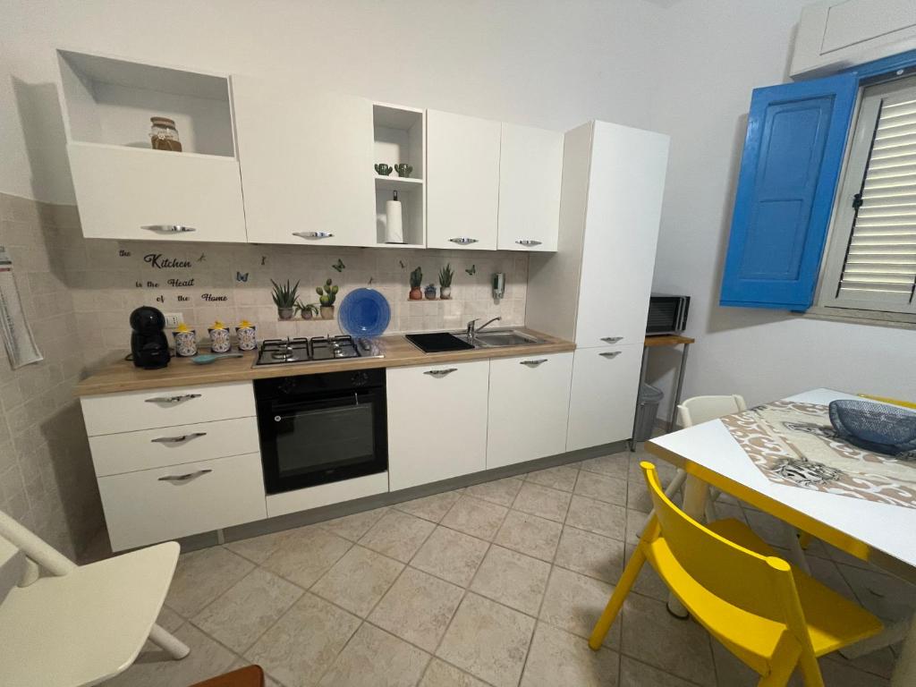 uma cozinha com armários brancos e uma mesa com uma cadeira amarela em Casa Vacanze J&F em Pozzallo