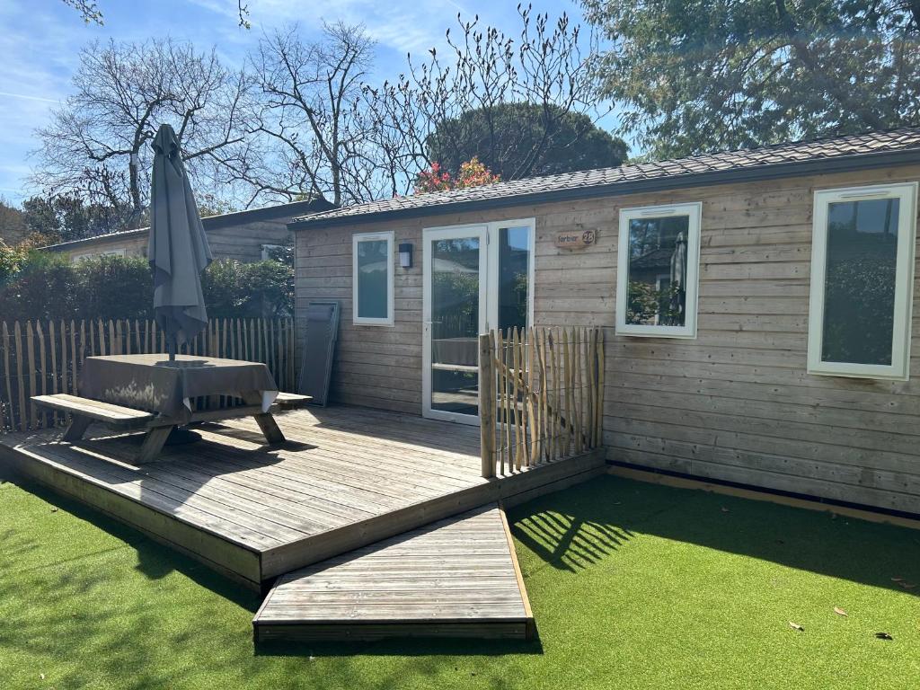 a wooden deck with a grill and an umbrella at Mobile home Grand Confort 30m² Modèle 1 in Arès