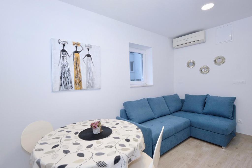 ein Wohnzimmer mit einem blauen Sofa und einem Tisch in der Unterkunft Apartment Smile in Solin