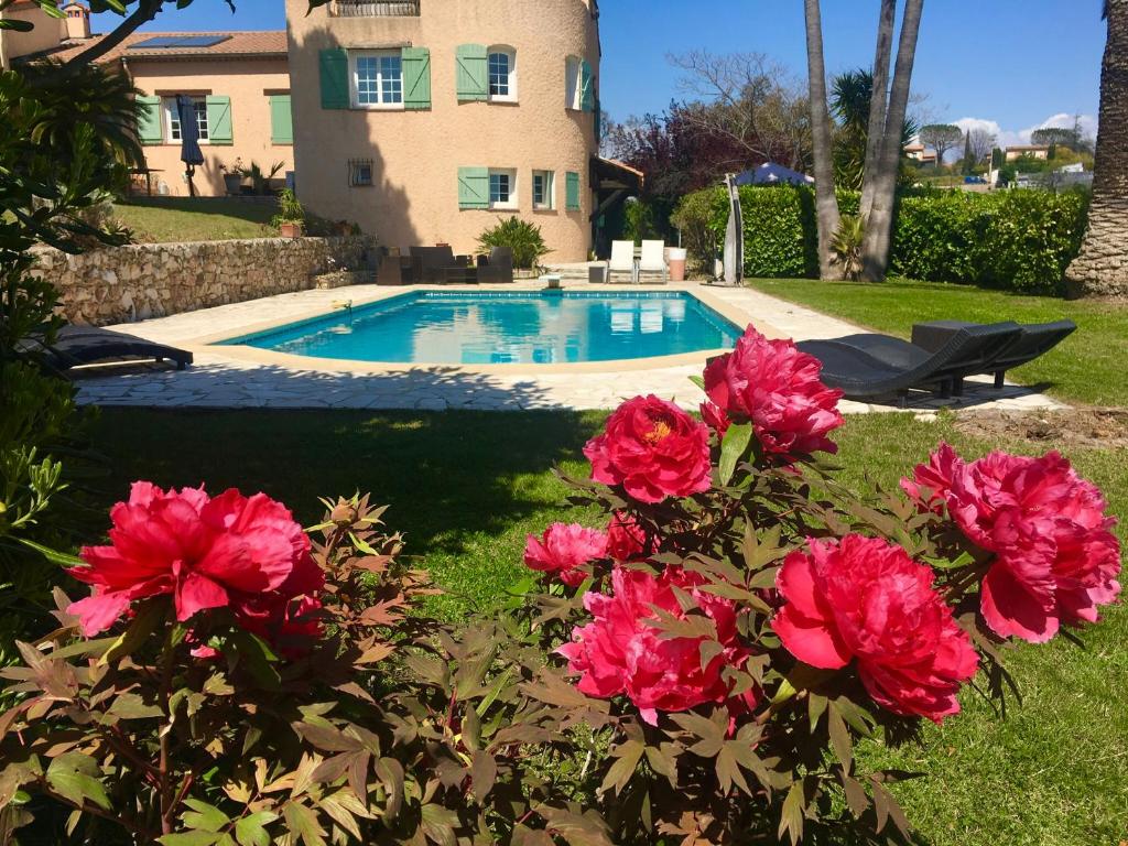 - une piscine avec des fleurs roses en face d'une maison dans l'établissement Villa Antoline, à Cagnes-sur-Mer