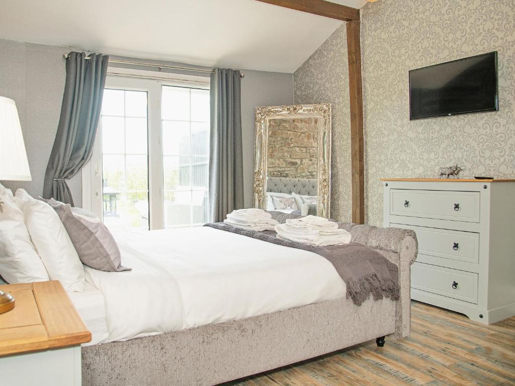 a bedroom with a large bed and a mirror at Acre Hill Cottage in Harrop Fold