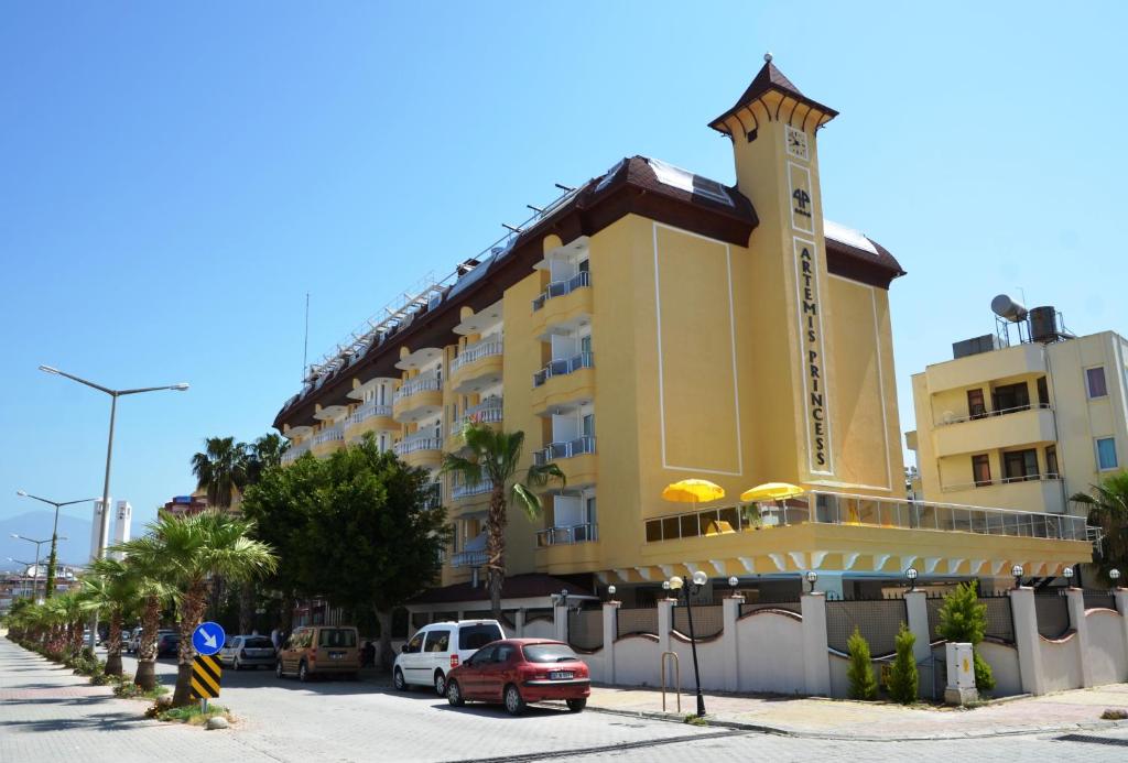 a yellow building with a clock tower on a street at Artemis Princess Hotel in Alanya