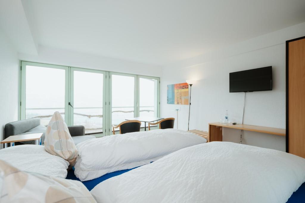 una camera d'albergo con due letti e una TV a schermo piatto di Hotel Sonne ad Amden