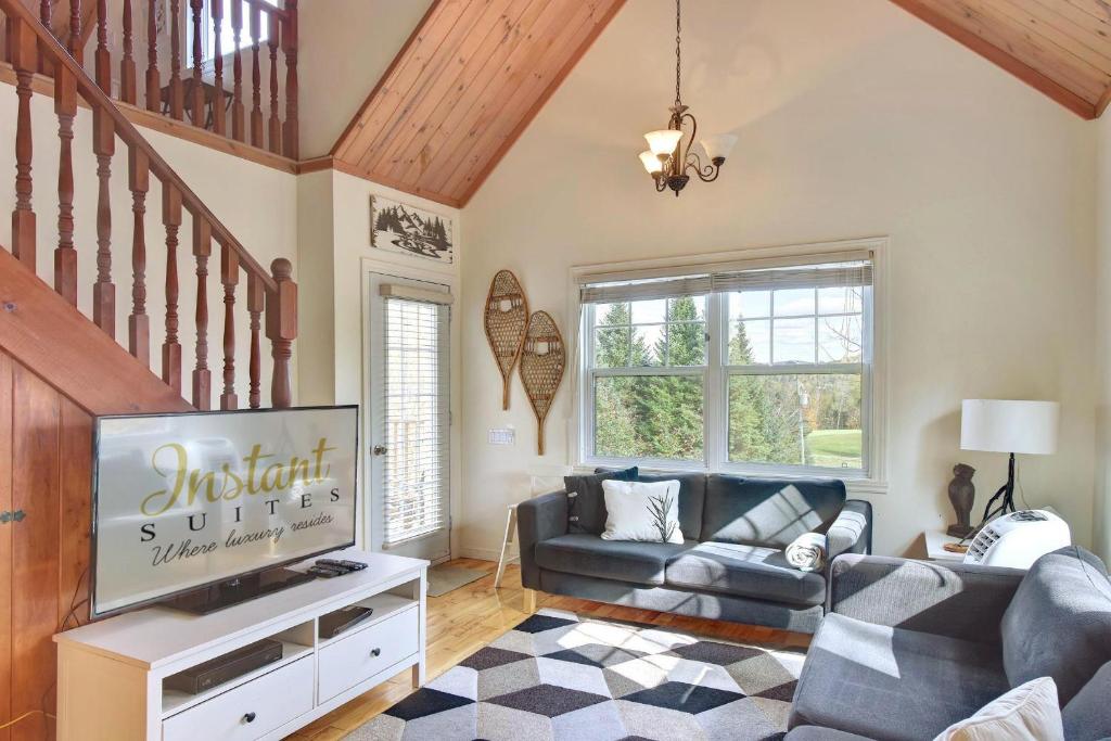 uma sala de estar com um sofá e uma televisão em The Golf & Mountain View Retreat by Instant Suites em Mont-Tremblant