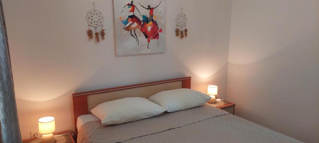 a bedroom with a bed with two lamps on two tables at Apartments Nikola Caska in Novalja