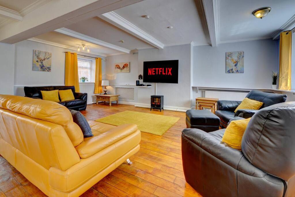 een woonkamer met lederen meubels en een televisie bij 6 bedrooms, sleeps up to 16, secure parking space & comfort in Skegby