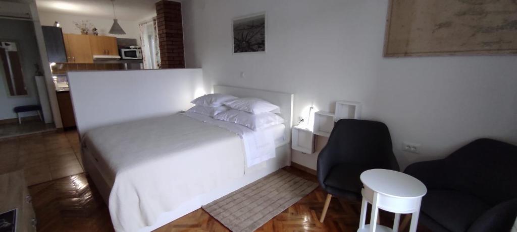 1 dormitorio con 1 cama blanca y 1 silla en Studio Apartment Riva en Sumartin