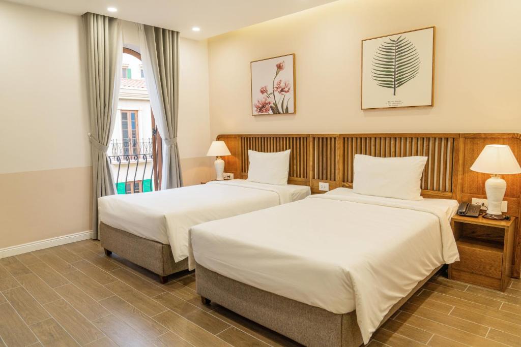 a hotel room with two beds and a window at Palo Santo Hotel Phu Quoc in Phu Quoc