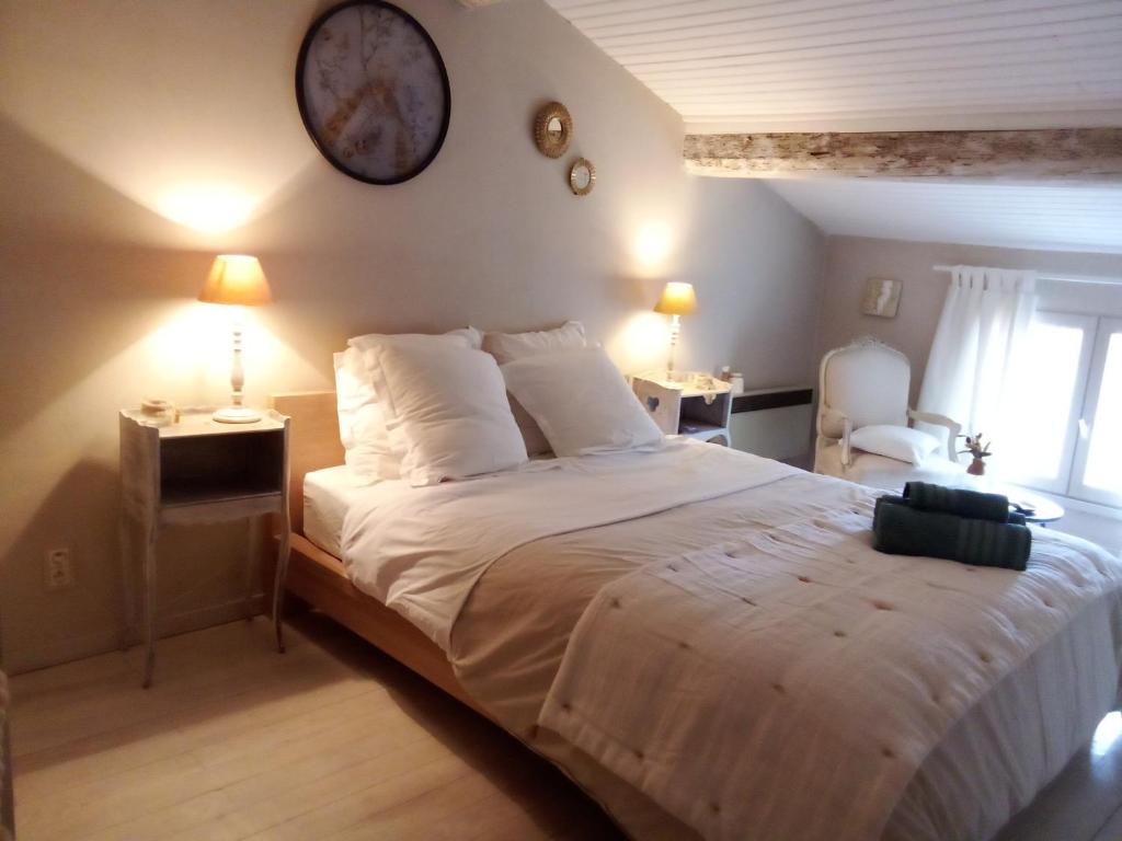 a bedroom with a large bed with a clock on the wall at La maison perchee in Aigues-Mortes