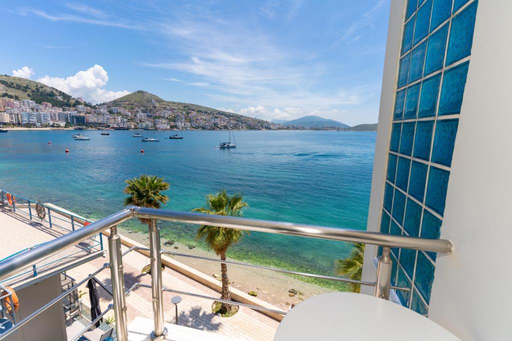 uma varanda com vista para a água e uma praia em Titania Hotel em Saranda