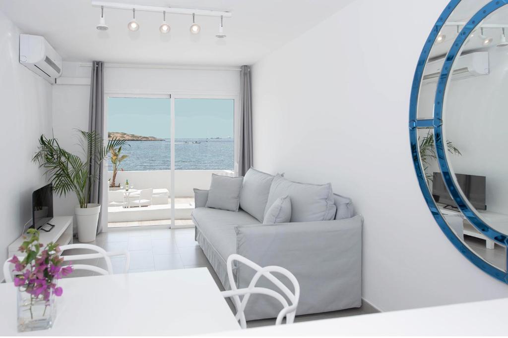 a white living room with a couch and a mirror at Enkala Apartamentos in Ibiza Town
