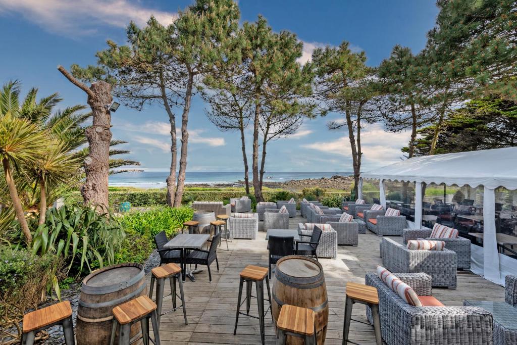 een patio met tafels, stoelen en bomen bij Le Theven in Sibiril