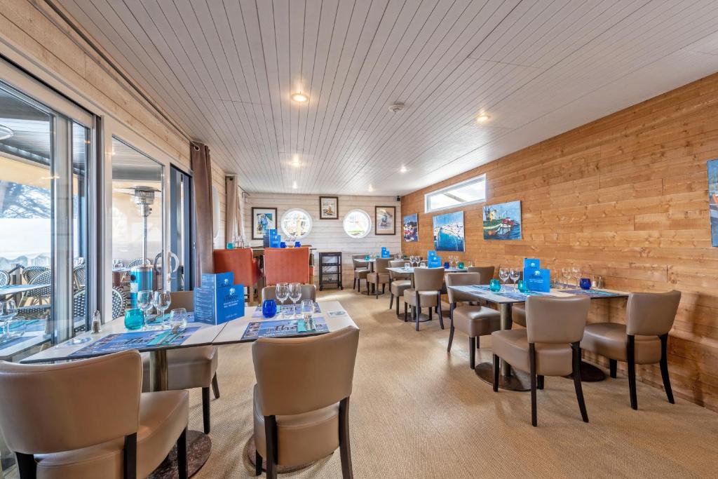 a dining room with tables and chairs and a brick wall at Le Theven in Sibiril