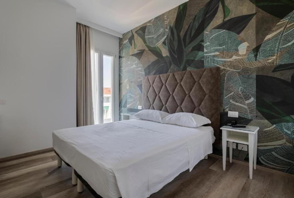 ein Schlafzimmer mit einem weißen Bett und einem Wandbild in der Unterkunft Hotel President in Lido di Jesolo