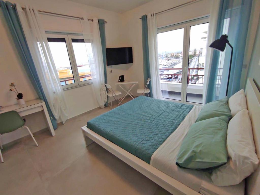 a bedroom with a bed and a desk and windows at B&B La Finestra sul Mare in Milazzo