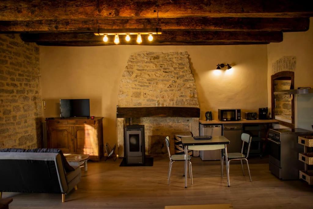 uma cozinha com mesa e cadeiras num quarto em CHEZ GUETOU Gîte de charme en Lozère em La Tieule