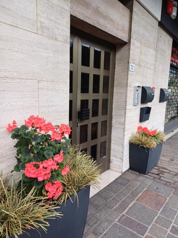 Deux pots de fleurs rouges devant un bâtiment dans l'établissement Il Geranio B&B, à Rovereto