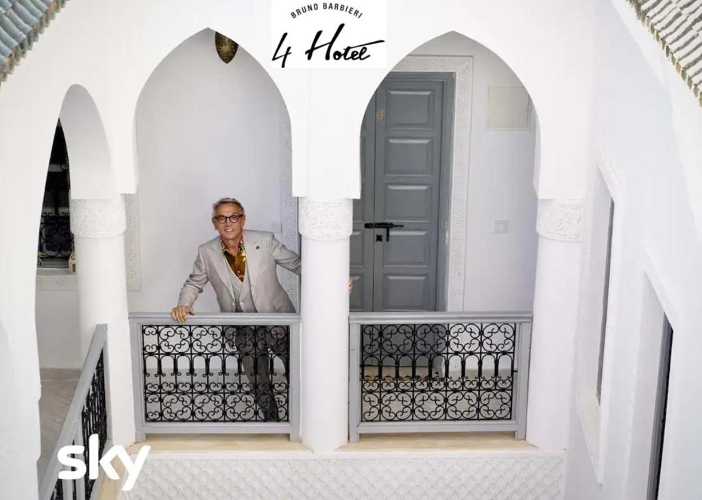 Ein Mann steht auf dem Balkon eines Hauses in der Unterkunft Riad El Arco ROOFTOP POOL & Spa in Marrakesch