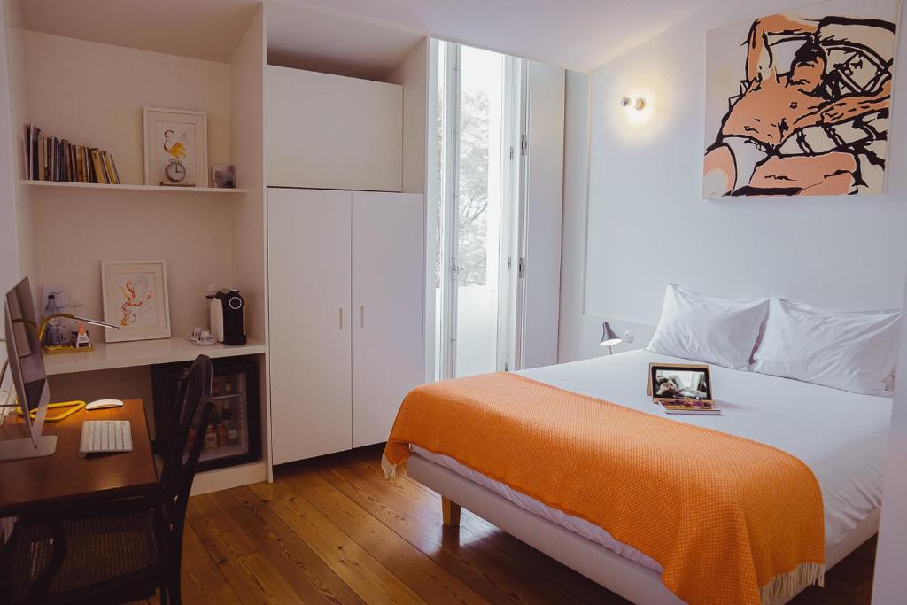 a bedroom with a bed with an orange blanket and a desk at The Late Birds Lisbon - Gay Urban Resort in Lisbon