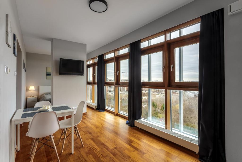 a living room with a table and chairs and windows at Vorto Apartament 3 - Warszawa Centrum in Warsaw