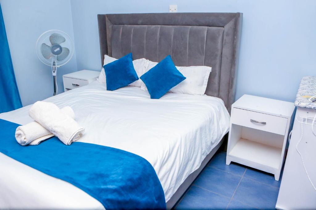 ein Schlafzimmer mit einem großen weißen Bett mit blauen Kissen in der Unterkunft Tiamcy homes in Kisumu