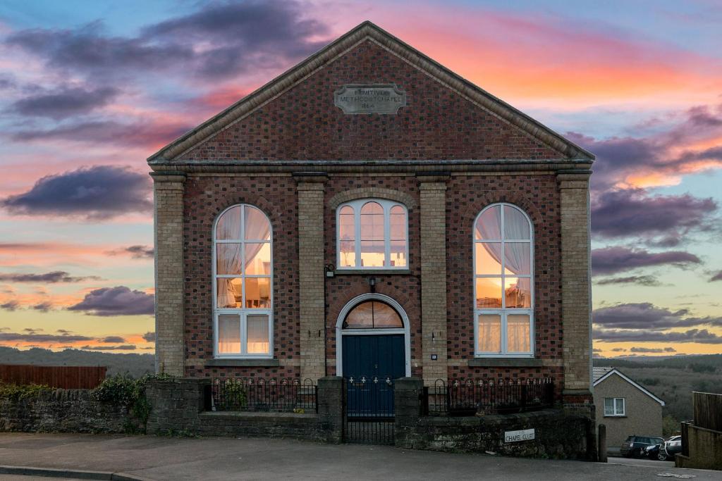 un bâtiment en briques avec un coucher de soleil en arrière-plan dans l'établissement Pew Corner at Chapel Collection, à Cinderford